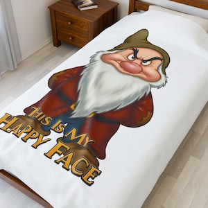 May include: White throw blanket featuring a grumpy dwarf cartoon character with the text "This is my happy face".