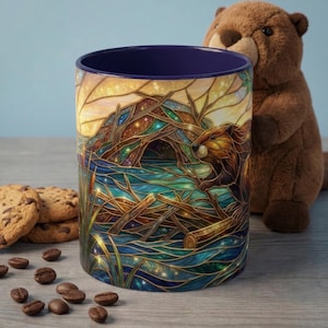 Może przedstawiać: Ceramiczny kubek z ilustracją w stylu witrażu przedstawiającą bobra i jego chatę. Kubek ma ciemnoniebieskie wnętrze i szczegółowy wzór przedstawiający bobra, wodę i drzewa. Ciasteczka z kawałkami czekolady i ziarna kawy na pierwszym planie.