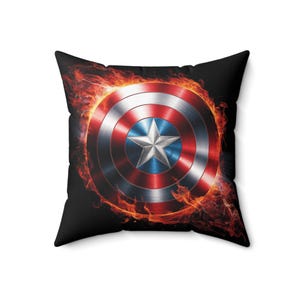 May include: A black pillow with a red, white, and blue Captain America shield surrounded by flames.