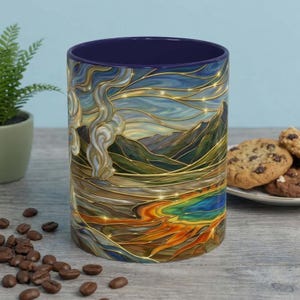 以下が含まれることがあります： 山、川、蒸気を描いたステンドグラスのデザインのセラミックコーヒーマグ。マグカップの内側は濃い青色です。コーヒー豆とクッキーが隣にあります。