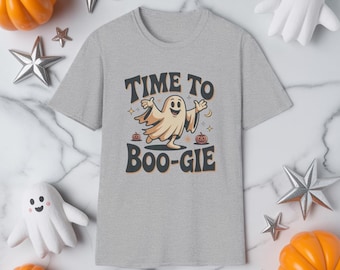 Könnte beinhalten: Hellgraues T-Shirt mit dem Text "TIME TO BOO-GIE" und einer Cartoon-Geistergrafik. Das Design umfasst Kürbisse und Sterne, perfekt für Halloween. Das T-Shirt ist von Halloween-Dekorationen umgeben.