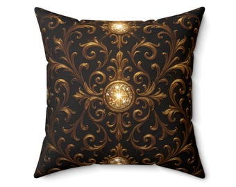 May include: Square cushion with a black backdrop and a gold baroque design. The pattern includes elaborate swirls and three large, sparkling, round, gold-coloured embellishments, creating a luxurious aesthetic.