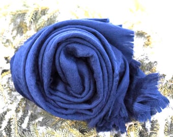 May include: A deep blue scarf rolled into a circular shape, featuring a soft, textured fabric surface and frayed edges at the end. The scarf is displayed with a consistent solid color throughout, showcasing a simple, unpatterned design.