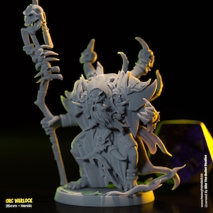 May include: A grey 35mm miniature figure of an Orc Warlock holding a staff with skulls. The figure is wearing a hooded robe and has a beard. The figure is standing on a base with a green and brown design.