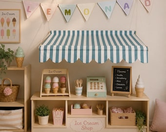 May include: A wooden toy ice cream shop stand featuring a blue and white striped fabric awning, a chalkboard menu listing flavors, a toy cash register, and various ice cream cone toys. Pastel bunting flags spelling LEMONAD hang above the unit.