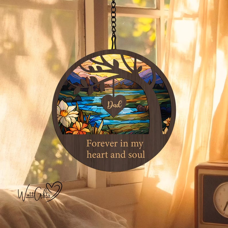 May include: A wooden circle with a stained glass design of a tree, river, and mountains. The text "Dad" is inside a heart shape and the text "Forever in my heart and soul" is below the stained glass design.