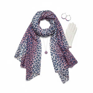 May include: A selection of accessories featuring a pink, blue, and white leopard print scarf, a pendant necklace, hoop earrings, and white gloves. The scarf is draped, and the items are arranged on a white background, showcasing a coordinated style.