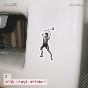 Peut inclure: Un autocollant en vinyle de 7,6 cm repr&eacute;sentant une illustration en noir et blanc d'une personne balan&ccedil;ant un marteau. L'autocollant porte le texte "100% vinyl sticker".