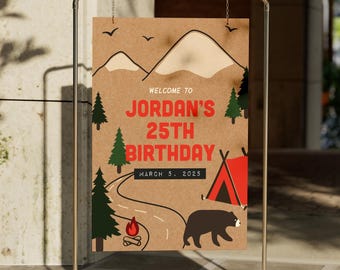以下が含まれることがあります： キャンプをテーマにした茶色の紙の看板。 「Welcome to Jordan's 25th Birthday」と2025年3月5日の日付が書かれています。 看板には、山、木、焚き火、テント、熊のイラストが描かれています。