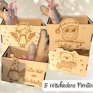 Könnte beinhalten: Vier Holzkisten mit Laserschnitt-Designs eines Engels, einer Eule, eines Bären und eines Zwergs. Jede Kiste enthält eine Kerze und dekorative Trockenblumen. Der Text "Du bist mir Wichtig" ist sichtbar.