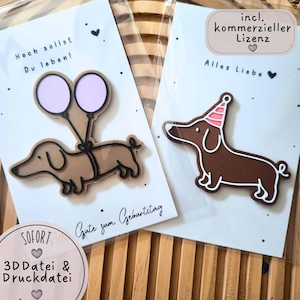 Pode incluir: Dois objetos de plástico em forma de cão salsicha em cartões brancos. Um cão salsicha bege segura dois balões roxos claros com o texto Hoch sollst Du leben! e Gute zum Geburtstag. O outro cão salsicha castanho usa um chapéu de festa rosa às riscas com Alles Liebe.