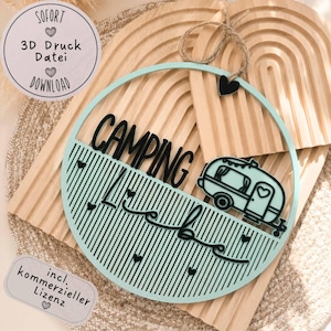 May include: A round, light blue camping sign with the word "CAMPING" in black, a camper illustration, and the words "Live Love" in script. The sign has a jute rope for hanging and small black heart accents.