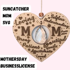 Puede incluir: Un atrapasol de madera en forma de corazón con un prisma de cristal colgando en el centro. El corazón está grabado con las palabras "Loving Mom Selfless Understanding Strong Patient Beautiful Gentle Affectionate Loved" y "Protective".