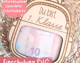 Puede incluir: Una tarjeta de madera con forma de mochila con el texto "Du bist 1. Klasse" y una ventana transparente que revela un billete de 10 euros. La tarjeta tiene el texto "Einschulung SVG" y "Sofortdownload Laserdatei Schüttelkarte".