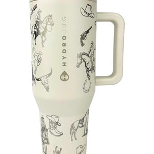 Puede incluir: Un vaso HydroJug de color crema con asa y tapa, adornado con ilustraciones de tem&aacute;tica vaquera en blanco y negro. El dise&ntilde;o incluye vaqueros a caballo, sombreros de vaquero, botas y herraduras. El texto "HydroJug" est&aacute; impreso en el lateral.