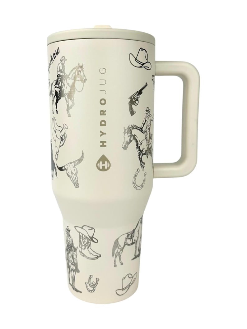 Puede incluir: Un vaso HydroJug de color crema con asa y tapa, adornado con ilustraciones de tem&aacute;tica vaquera en blanco y negro. El dise&ntilde;o incluye vaqueros a caballo, sombreros de vaquero, botas y herraduras. El texto "HydroJug" est&aacute; impreso en el lateral.