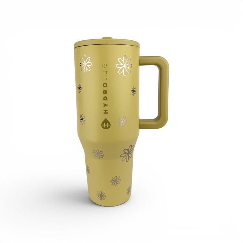 May include: A mustard yellow insulated tumbler with a side handle and a lid. The exterior features a repeating pattern of small, metallic silver flower outlines. The text HYDROJUG and a dumbbell icon are printed vertically in silver on the front.