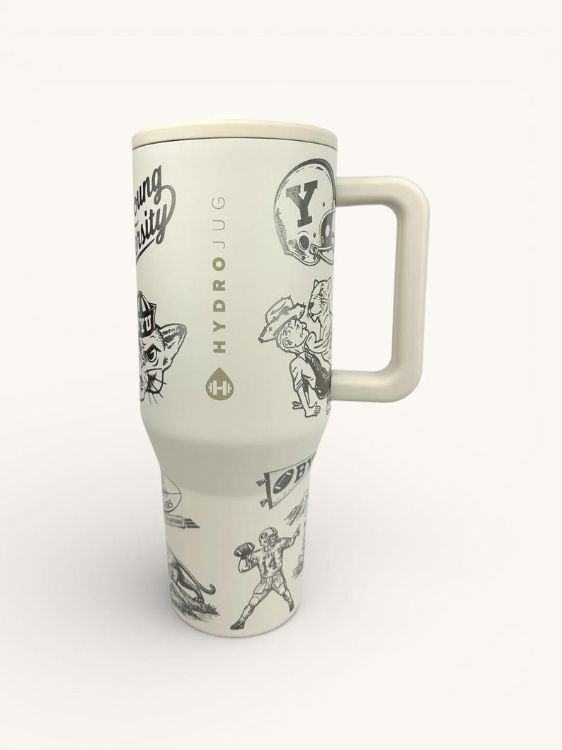 以下が含まれることがあります： クリーム色のHydroJug。大学をテーマにした白黒イラストが描かれています。ジャグにはハンドルと蓋が付いています。「HYDROJUG」の文字が側面に縦に印刷されています。フットボール選手など、さまざまなイラストで装飾されています。