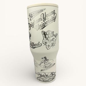 以下が含まれることがあります： ブリガムヤング大学のグラフィックが施された白いタンブラー。デザインには「Brigham Young University」の文字、クーガーのマスコット、「Cougars」と「Shout」の文字が含まれています。タンブラーにはクリーム色の蓋が付いています。