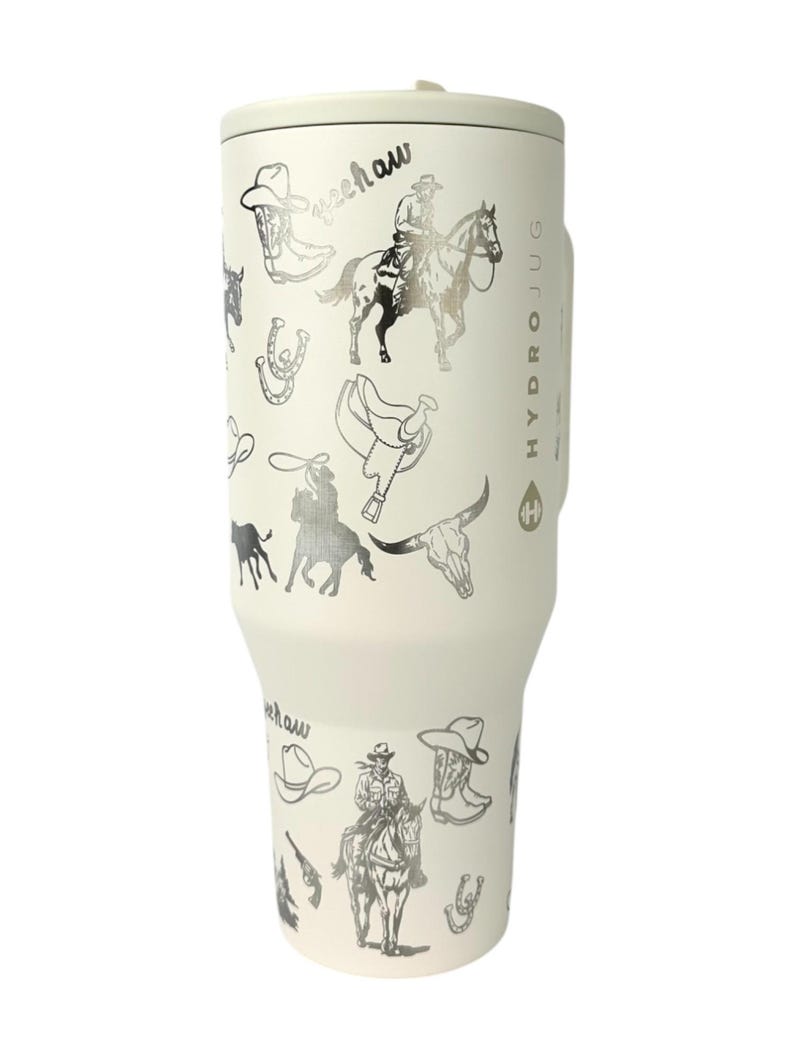 Puede incluir: Botella de agua HydroJug blanquecina con un dise&ntilde;o plateado con tem&aacute;tica de vaquero. El dise&ntilde;o incluye botas de vaquero, sombreros, caballos y la palabra "yeehaw". La botella tiene un asa y una tapa.