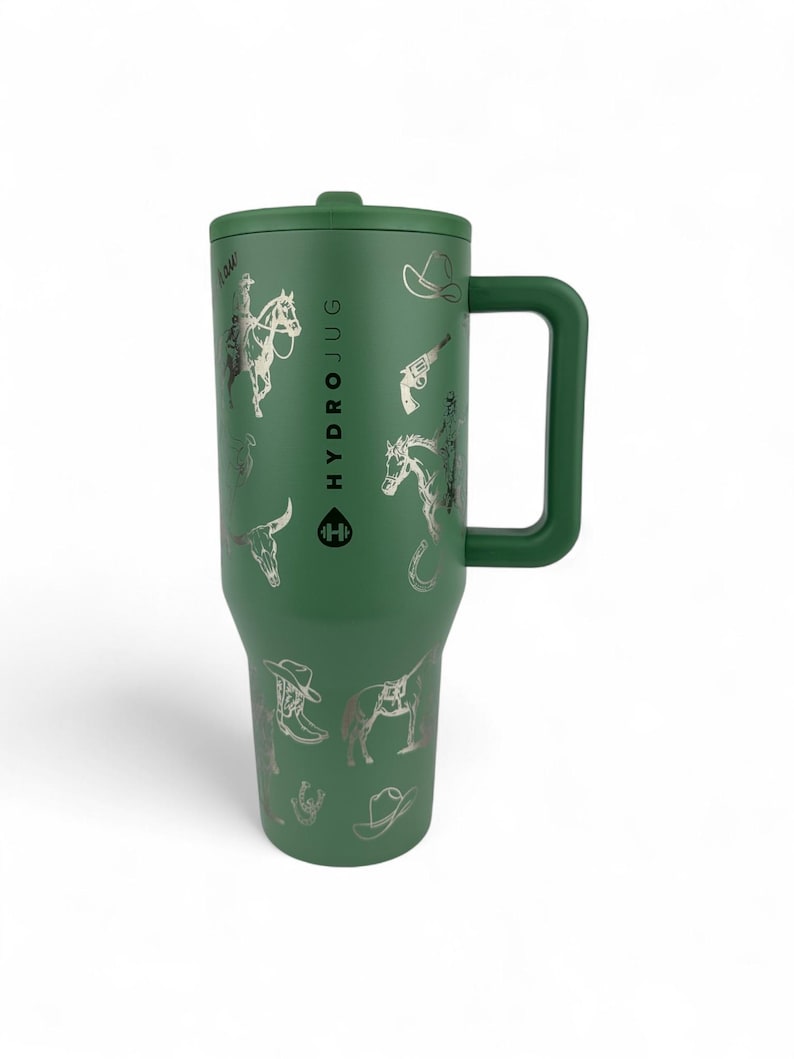 Puede incluir: HydroJug verde con asa y tapa, adornado con ilustraciones plateadas con tem&aacute;tica de vaqueros. El dise&ntilde;o incluye im&aacute;genes de un vaquero a caballo, un sombrero de vaquero, una pistola, una herradura y una cabeza de toro. El logotipo de HydroJug es visible.