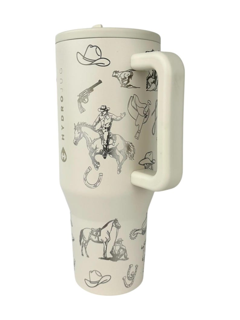 Puede incluir: Vaso t&eacute;rmico aislado de color crema con asa y tapa, con tem&aacute;tica de vaquero. El vaso est&aacute; decorado con ilustraciones en negro y plata de sombreros de vaquero, caballos, sillas de montar y un vaquero montado a caballo. El texto "HYDROJUG" est&aacute; impreso verticalmente.