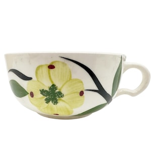 May include: A white ceramic soup bowl with a floral design. The bowl features a yellow flower with red accents and green leaves on a white background.