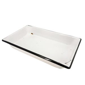 May include: A rectangular white enamel tray with a black rim. The tray features a smooth, glossy finish on the interior and exterior surfaces, with a small brown spot visible on the inner base and minor surface imperfections throughout the white coating.