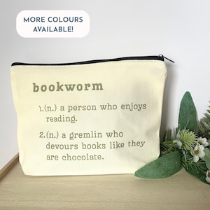 May include: A cream-coloured canvas pouch with a black zip, printed with the word "bookworm" in grey. The definition below describes a person who enjoys reading and a gremlin who devours books. A white oval with the text "MORE COLOURS AVAILABLE!" is in the top left.