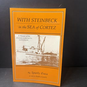 Könnte beinhalten: Ein Taschenbuch mit orangefarbenem Einband, betitelt "WITH STEINBECK in the SEA of CORTEZ" mit weißem Text. Das Cover zeigt eine Schwarz-Weiß-Illustration eines Bootes und den Text "A Memoir of the STEINBECK/RICKETTS EXPEDITION".