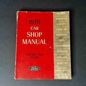 Puede incluir: Un manual de taller de automóviles Ford rojo de 1970, volumen dos: Motor. La portada presenta el logotipo de Ford y una lista de modelos de automóviles que incluyen Meteor, Maverick, Falcon, Fairlane, Mustang, Thunderbird, Montego, Cougar, Mercury, Lincoln Continental y Continental Mark III.