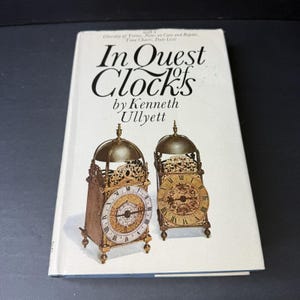 May include: A book titled "In Quest of Clocks" by Kenneth Ullyett. The cover features two antique clocks with ornate details and Roman numeral faces.