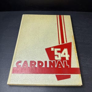 Puede incluir: Un anuario vintage con una cubierta color crema. La portada presenta la palabra "CARDINAL" en letras rojas, con el año "'54" en un diseño geométrico rojo. Rayas rojas verticales acentúan la parte superior.