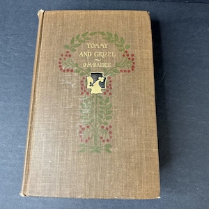 Peut inclure: Un livre brun avec un titre doré et un motif décoratif. Le titre est "Tommy and Grizel" par J.M. Barrie.
