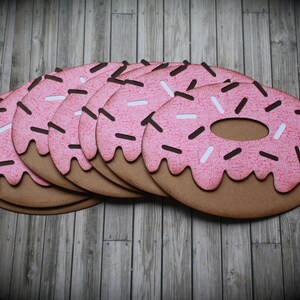 May include: A stack of pink and brown donut-shaped paper cutouts with white and brown sprinkles.