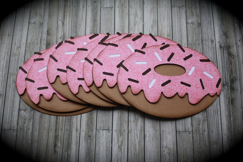 May include: A stack of pink and brown donut-shaped paper cutouts with white and brown sprinkles.
