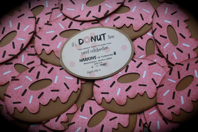 May include: It's donut time! A pink and brown donut-shaped invitation with white and brown sprinkles. The invitation reads "It's donut time! You donut want to miss this sweet celebration. Harkins is turning 8. Wednesday, March 23rd, 3-5 p.m. RSVP by March 10."