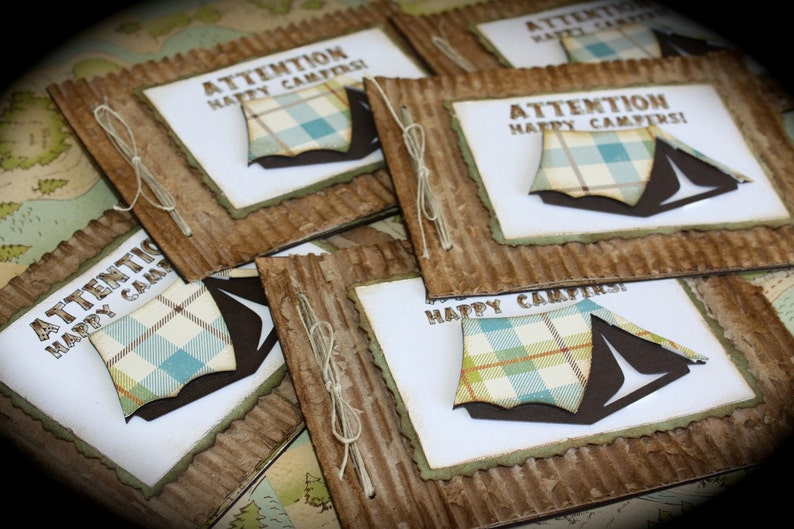 May include: A stack of brown cardstock cards with a white background and a blue and white plaid tent design. The text on the cards reads "Attention Happy Campers!"