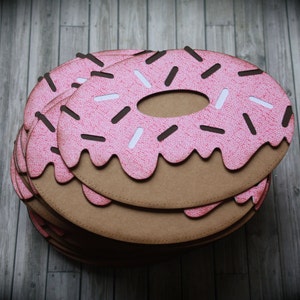 May include: A stack of pink and brown paper donuts with white and brown sprinkles. The donuts are layered on top of each other.