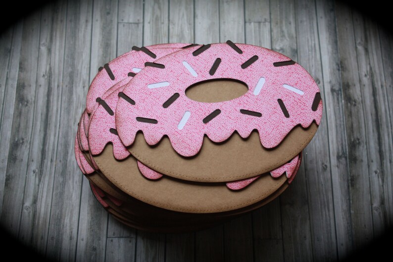 May include: A stack of pink and brown paper donuts with white and brown sprinkles. The donuts are layered on top of each other.