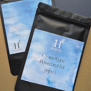 May include: Two black pouches with blue watercolor-style labels. The labels read "Cyanotype Postcard Kit (6pc)" and include instructions and the brand name "HINOKI". The kits are designed for sun printing.