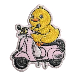 May include: An embroidered yellow chick riding a pink scooter. The scooter has black wheels and white trim.