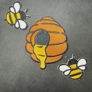 May include: Three embroidered iron-on patches featuring a beehive with dripping honey and two bees with black and yellow stripes.