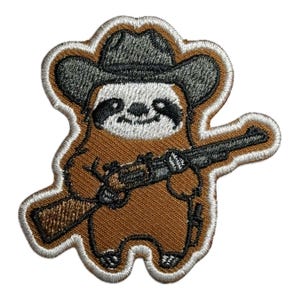 Puede incluir: Parche bordado de un perezoso marrón que lleva un sombrero de vaquero y sostiene un rifle. El perezoso tiene una cara blanca con ojos negros y una nariz negra.