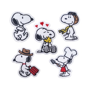 Könnte beinhalten: Satz von sechs gestickten Bügeletiketten mit verschiedenen Variationen der Zeichentrickfigur Snoopy. Die Etiketten sind weiß mit schwarzen Umrissen und zeigen verschiedene Gesichtsausdrücke und Accessoires.