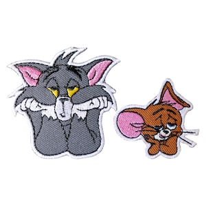 May include: Tom and Jerry cartoon character iron-on patches. Tom is a grey cat with yellow eyes and is shown with his arms crossed. Jerry is a brown mouse with pink ears and is shown with his arms crossed.