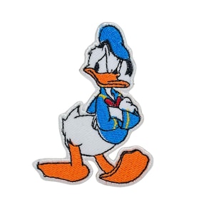 Op de afbeelding: Geborduurde patch met Donald Duck, een tekenfilm eend in een blauw matrozenpak, hoed en oranje voeten. De patch heeft een witte rand op een witte achtergrond. De uitdrukking van het personage lijkt verdrietig.