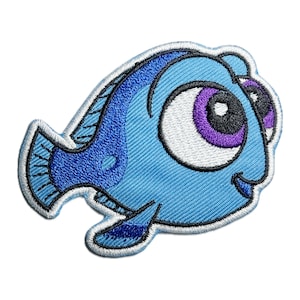 May include: A blue and purple embroidered patch of a cartoon fish with big eyes. The fish is smiling and has a white outline.