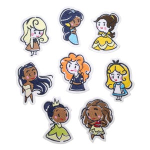 Może przedstawiać: Kolekcja haftowanych naszywek przedstawiających kreskówkowe wizerunki różnych księżniczek. Każda naszywka przedstawia inną księżniczkę, taką jak Jasmine i Bella, z unikalnymi fryzurami i strojami. Naszywki są obramowane na biało.