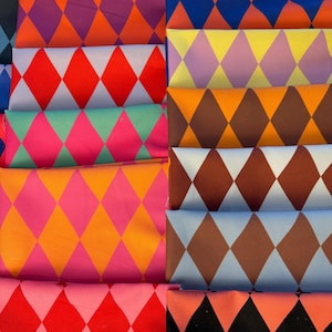 Può includere: Una collezione di pezzi di tessuto piegati con un motivo a rombi ripetuto. I tessuti presentano una varietà di colori, tra cui rosso, rosa, arancione, marrone, blu e giallo. Le forme a rombo sono in colori contrastanti.